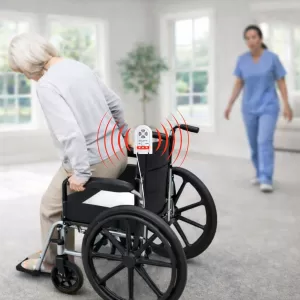 Elderly woman exiting a wheelchair with chair alarm sounding. A nurse is walking toward the woman to assist and prevent a fall.