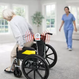 Elderly woman exiting a wheelchair with chair alarm sounding. A nurse is walking toward the woman to assist and prevent a fall.